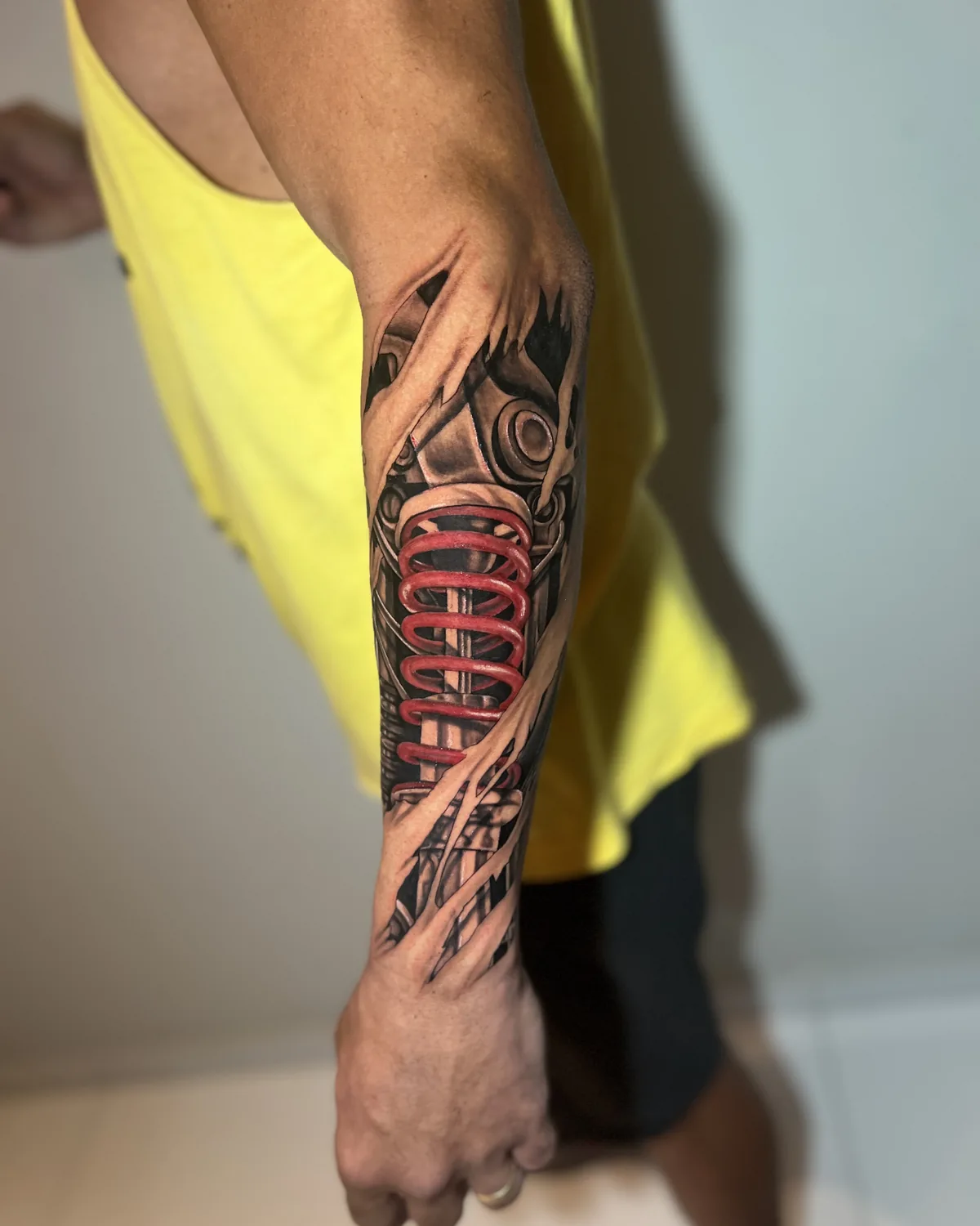 Tatuagem biomecânica de amortecedor vermelho sob a pele rasgada, no antebraço